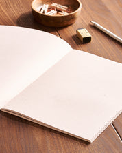 Open eco-friendly notebook with blank recycled pages on wooden table with pencil and eraser nearby