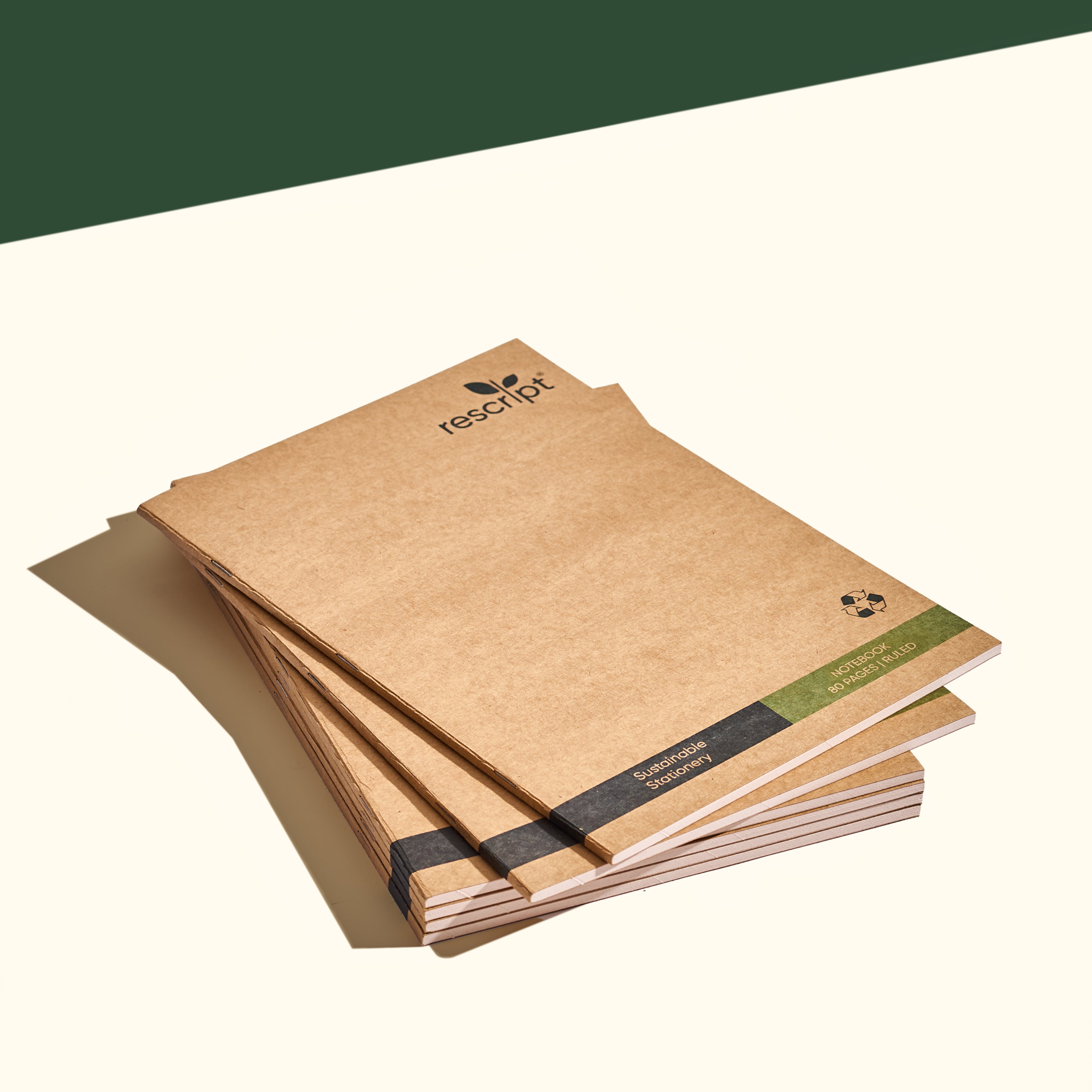 Stack of six eco-friendly recycled paper notebooks with neutral brown covers and minimal green and black accents